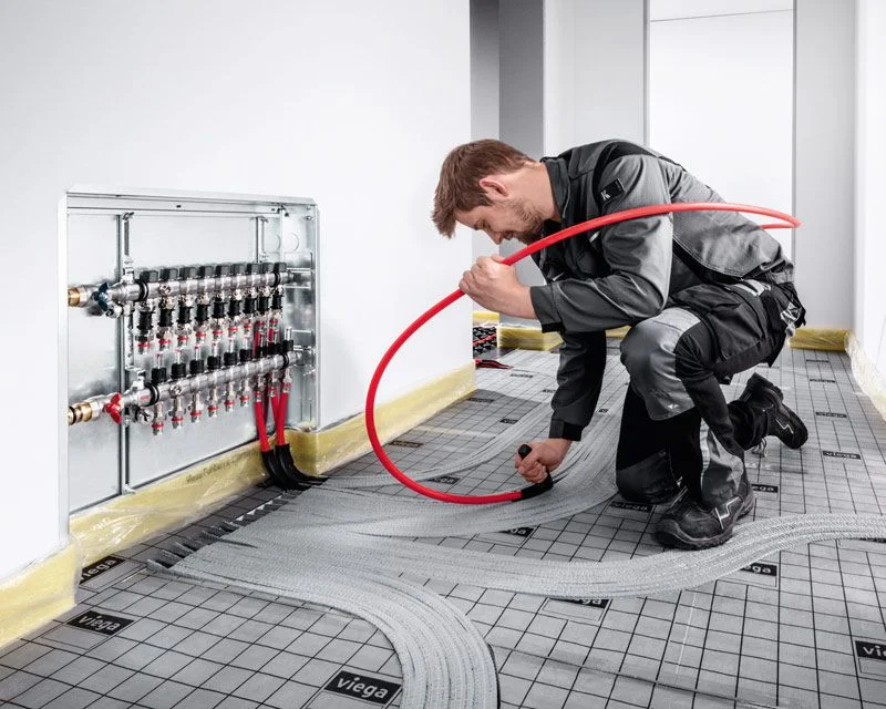 Ein Heizungsinstallateur verlegt eine Fußbodenheizung.